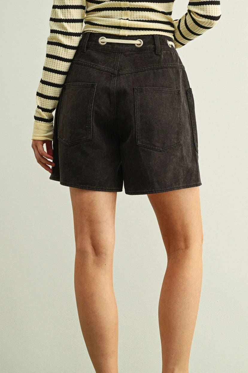 Person wearing black shorts and a striped shirt on a plain background
