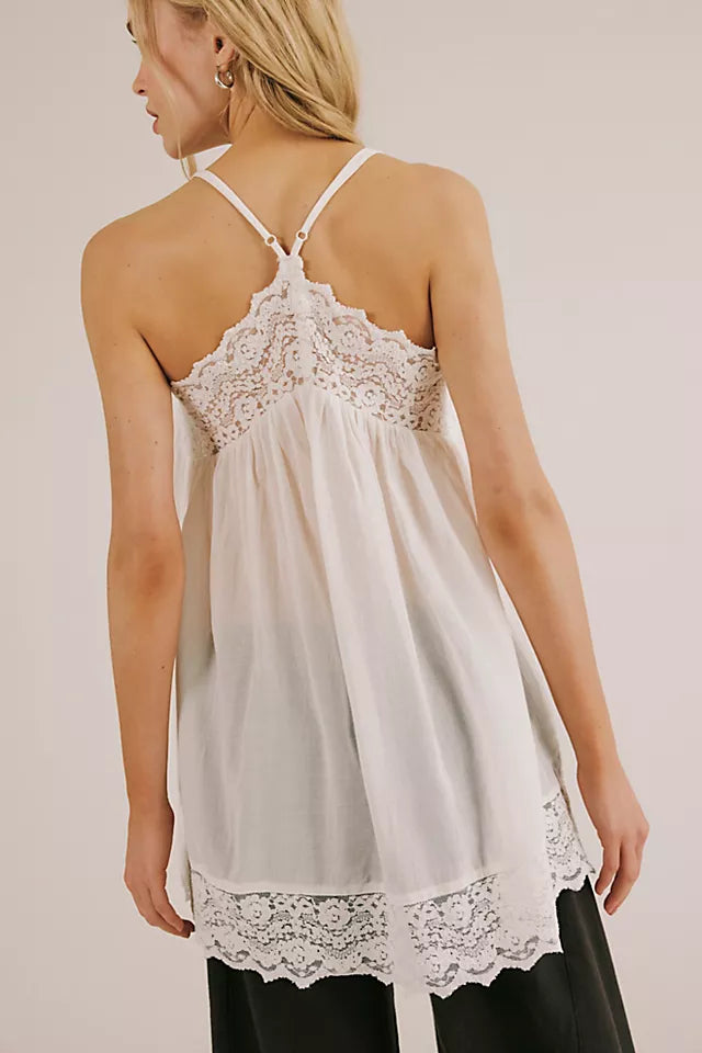 Woman wearing a white lace-trimmed camisole against a plain background