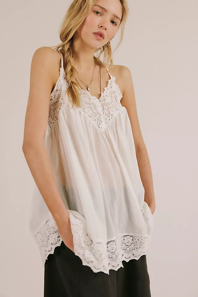 Woman wearing a white lace-trimmed top against a plain background